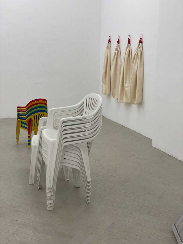 Ausstellungsansicht im Frise Künstler*innenhaus: Detailansicht mit Plastikstühlen und Schürzen